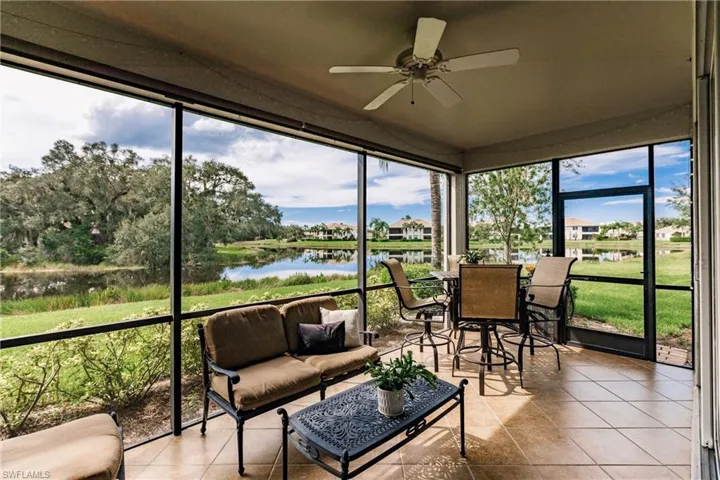 Sunroom with ceiling fan, tile patterned flooring, a water view, and expansive windows