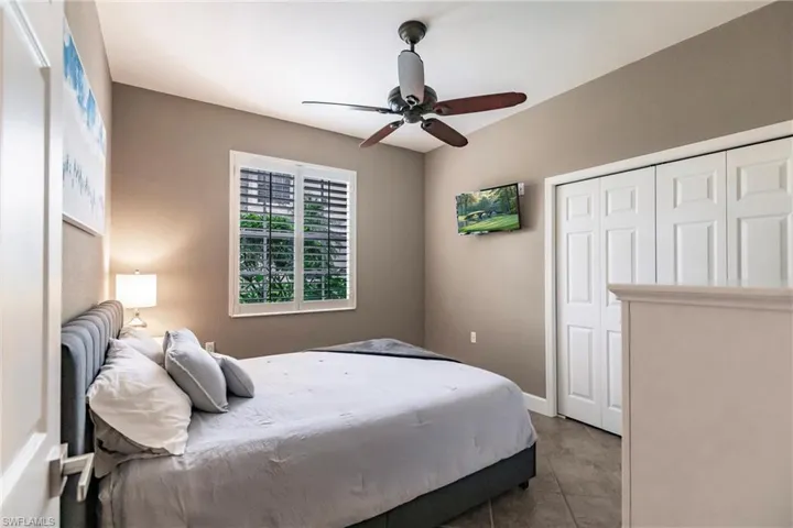 Bedroom with ceiling fan, tile patterned flooring, and a closet