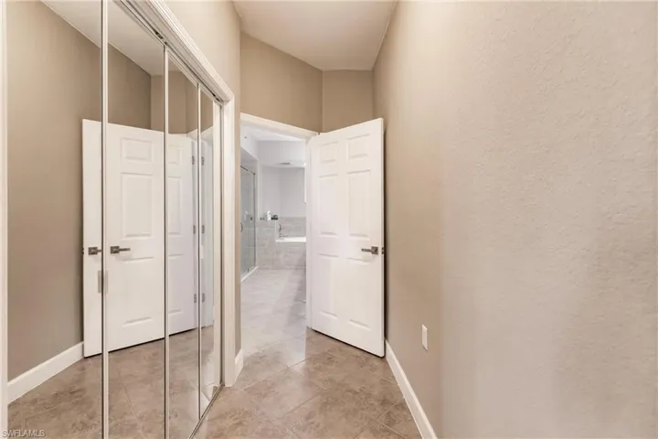 Corridor with light tile patterned flooring and baseboards