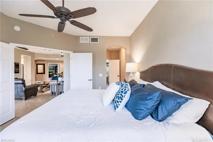 Bedroom with light tile patterned flooring, arched walkways, and a ceiling fan