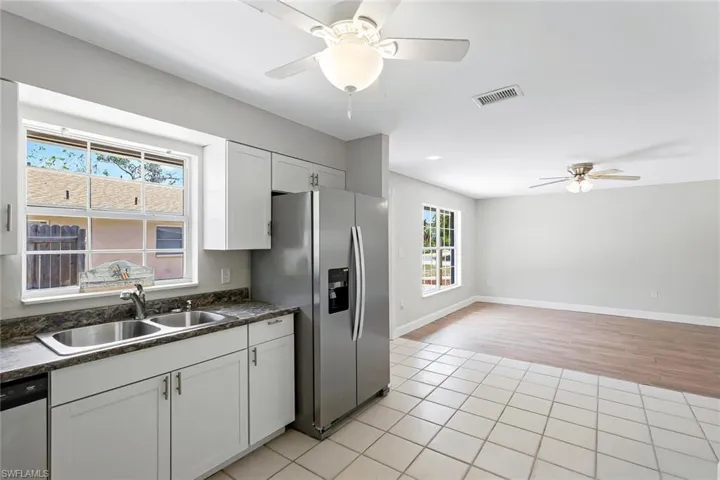 Kitchen with stainless steel appliances, ceiling fan, dark countertops, light wood finished floors, and white cabinets
