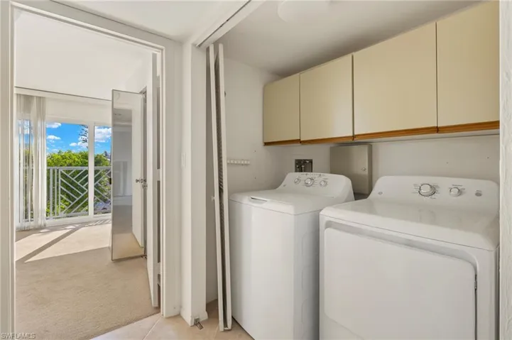 Laundry area featuring independent washer and dryer, light carpet, and cabinets