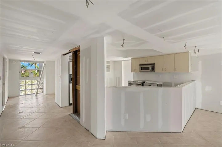 Kitchen featuring stainless steel microwave, light tile patterned floors, and cream cabinetry