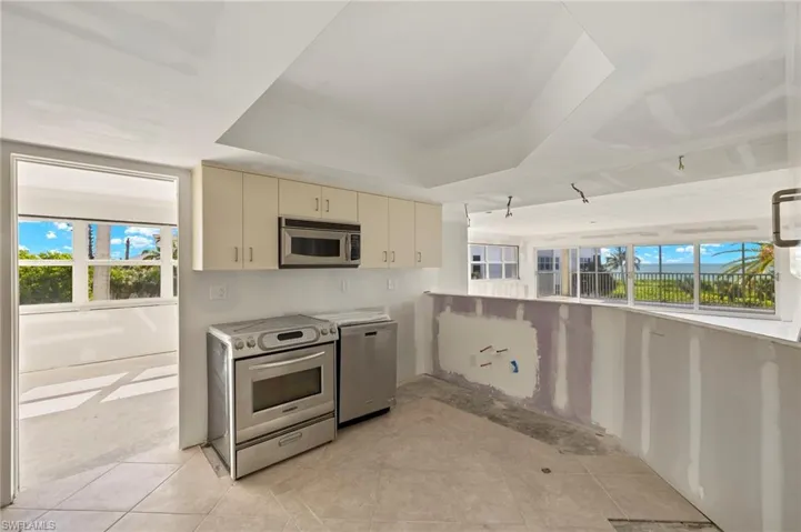 Kitchen with stainless steel appliances, a tray ceiling, a wealth of natural light, and cream cabinets