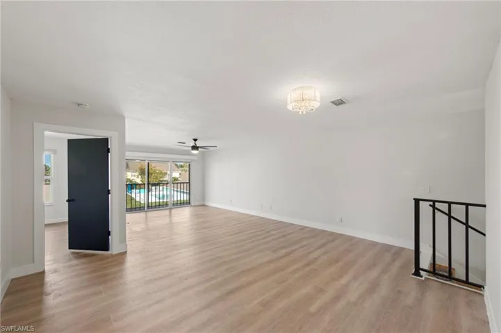 Empty room with light wood-style floors, ceiling fan, and suspended lighting
