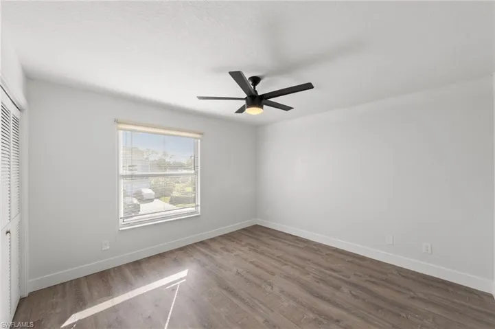 Unfurnished bedroom with a closet, dark wood finished floors, and a ceiling fan