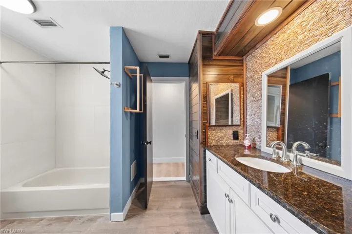 Bathroom featuring vanity, shower / bathtub combination, a textured ceiling, and light wood-style floors