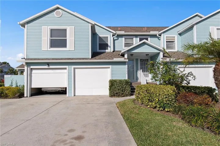 Traditional-style house featuring driveway, an attached garage, and a shingled roof