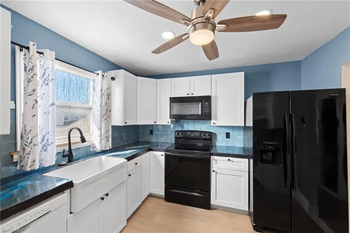 Kitchen with black appliances, white cabinetry, light wood-type flooring, tasteful backsplash, and recessed lighting