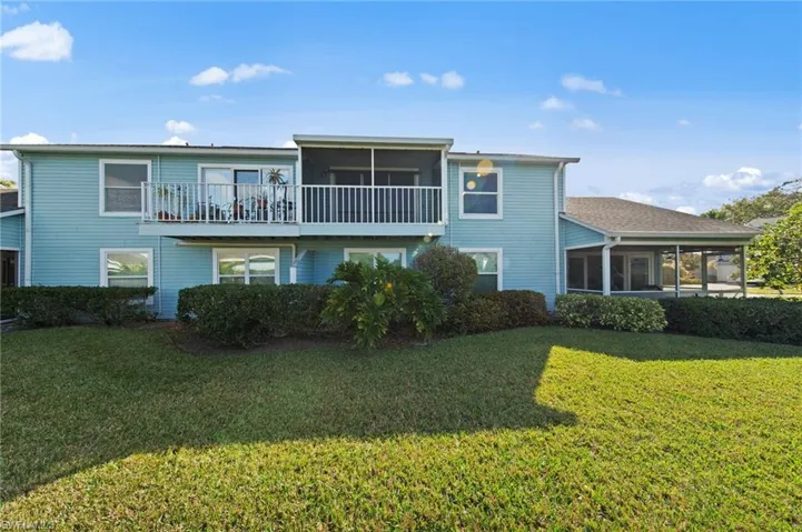 Rear view of house with a sunroom, a balcony, and a yard