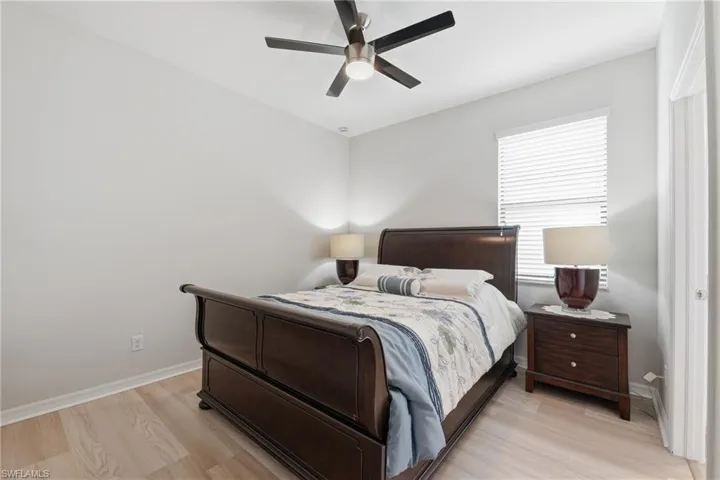 Room featuring light wood-finish flooring, a ceiling fan with integrated lighting, and a window with horizontal blinds