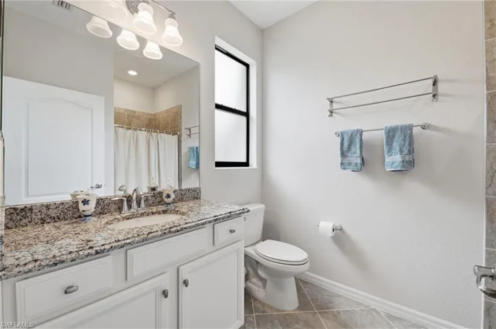 Bathroom featuring a white vanity with a granite countertop and an undermount sink