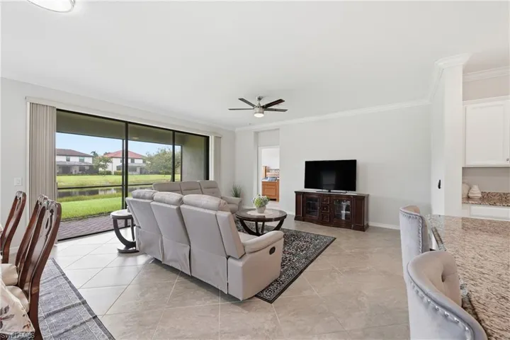 Open-concept living space featuring tiled flooring, crown molding, and a ceiling fan