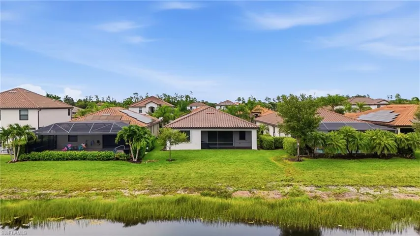 Single-story residence featuring a screened-in lanai, tile roof, and expansive green space