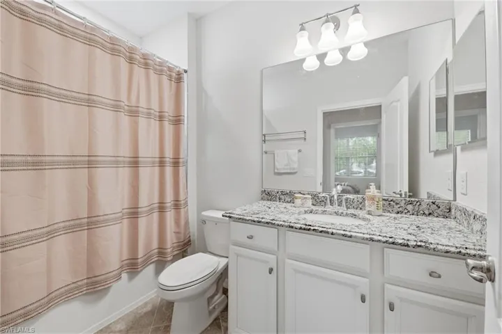 Bathroom featuring a white vanity with shaker-style cabinetry, a granite-finish countertop, and an undermount sink