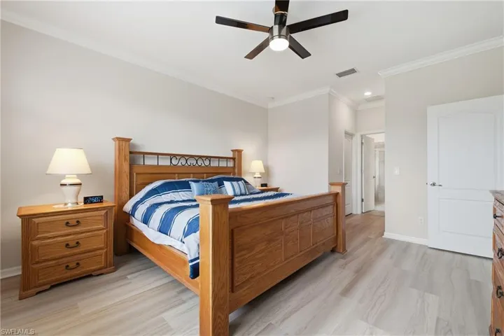 Spacious room featuring wood-finish flooring, crown molding, and a ceiling fan with integrated lighting