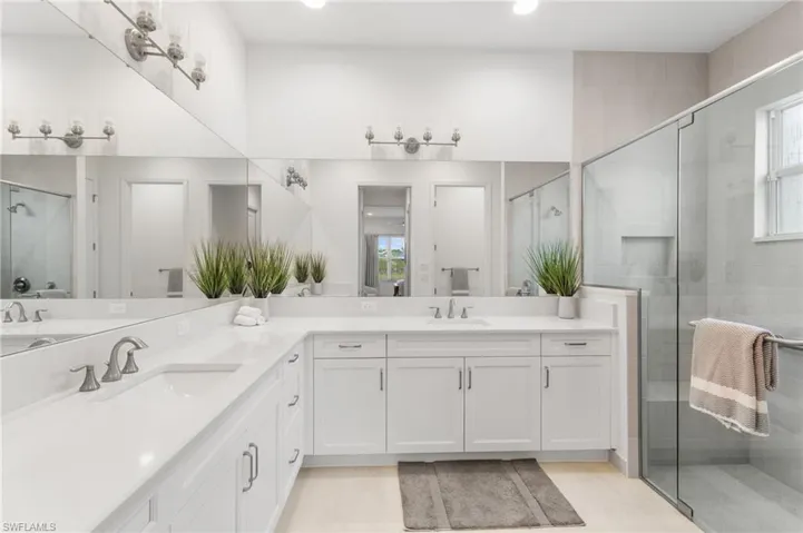 Bathroom featuring a shower stall, double vanity, plenty of natural light, and recessed lighting