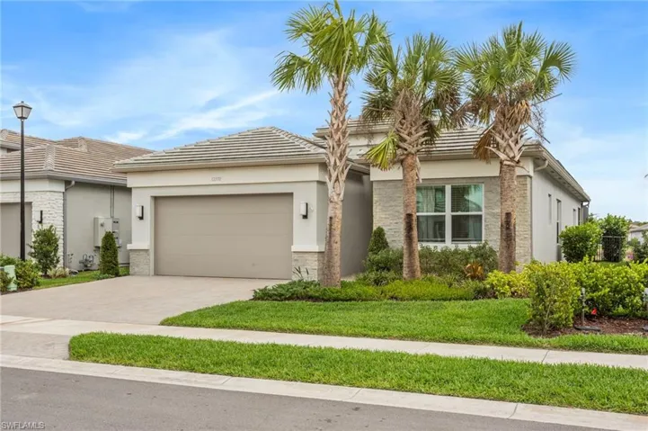 View of front of home with decorative driveway, a garage, stucco siding, and a front yard