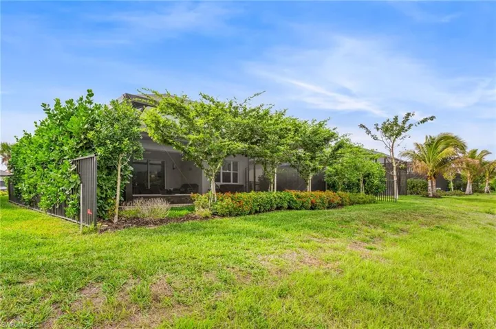 Rear view of house featuring a yard, glass enclosure, and a sunroom
