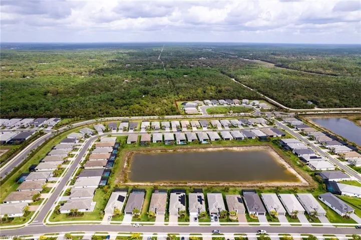 Aerial view of residential area with a nearby body of water and a forest