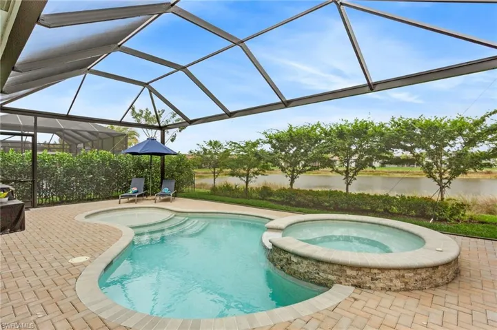 Combined pool / hot tub with a sunroom, a lanai, a patio area, and a water view