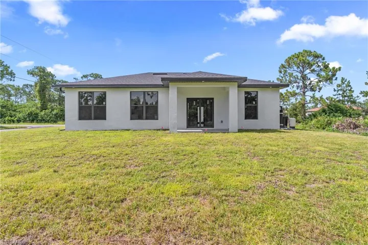 Rear view of property featuring stucco siding and a yard