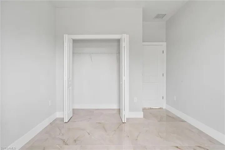 Unfurnished bedroom with marble finish floors and a closet