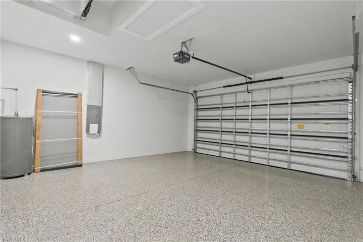 Garage with electric panel, water heater, and a garage door opener