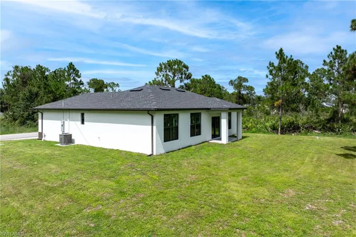 Rear view of house featuring a lawn and stucco siding
