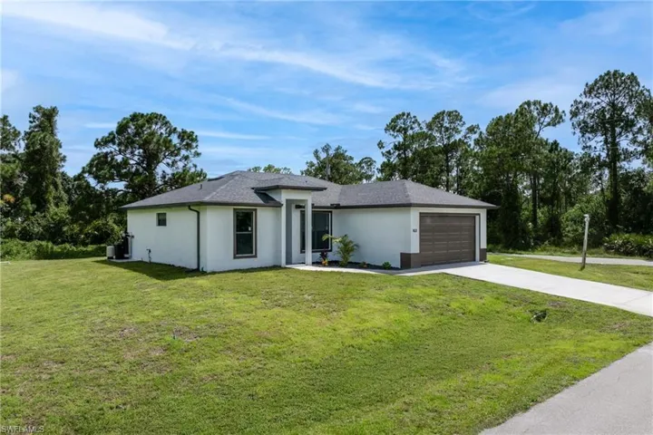 View of front of home with driveway, a front yard, a garage, and stucco siding