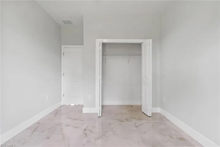 Unfurnished bedroom featuring marble finish floors and a closet