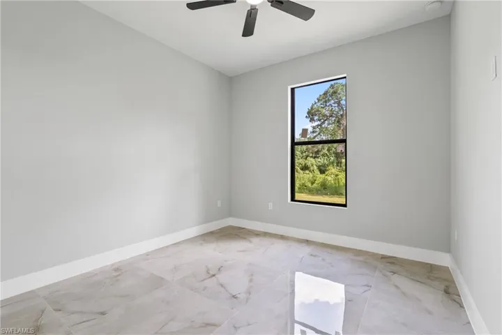 Unfurnished room featuring light marble finish floors and ceiling fan
