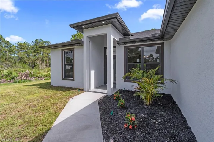 View of exterior entry featuring stucco siding and a lawn