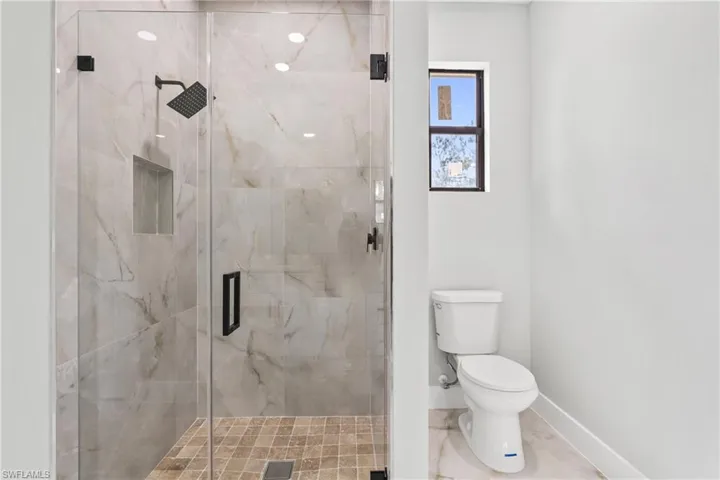 Bathroom featuring toilet and a marble finish shower