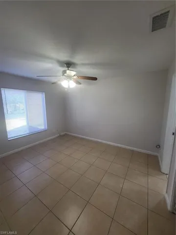 Empty room featuring a ceiling fan and light tile patterned floors