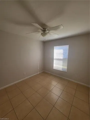 Unfurnished room featuring light tile patterned flooring and ceiling fan