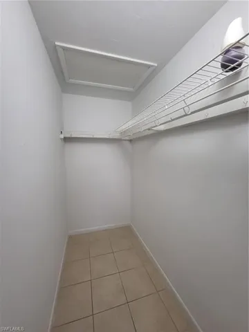 Walk in closet with light tile patterned flooring and attic access
