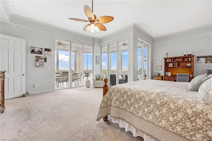 The primary suite offers three sets of sliding glass doors showcasing spectacular views, complemented by crown molding and plush carpeting that adds warmth and a touch of luxury.