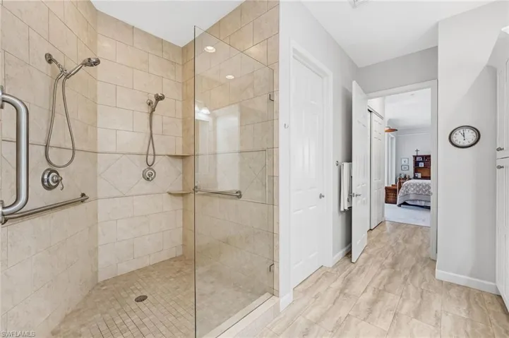 The spa-inspired walk-in shower boasts floor-to-ceiling subway tile, a seamless glass enclosure, and two showerheads, delivering both elegance and luxury.