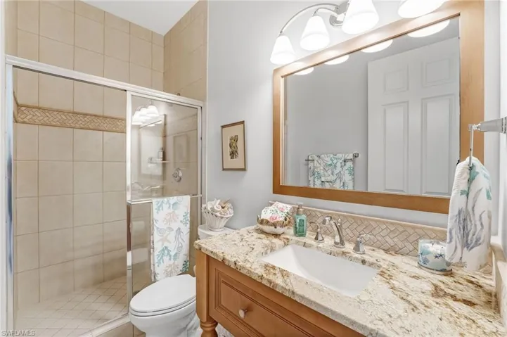The beautifully appointed second bathroom offers custom cabinetry, granite countertops, and a luxurious walk-in shower finished with floor-to-ceiling porcelain tile.