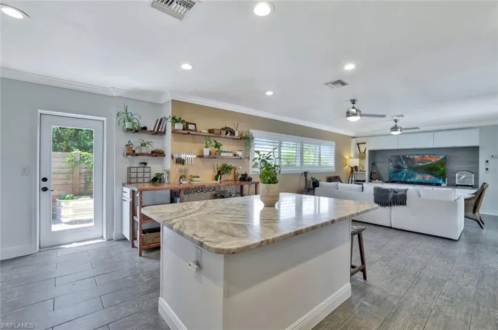Kitchen with a healthy amount of sunlight, hardwood / wood-style flooring, ceiling fan, and a kitchen bar