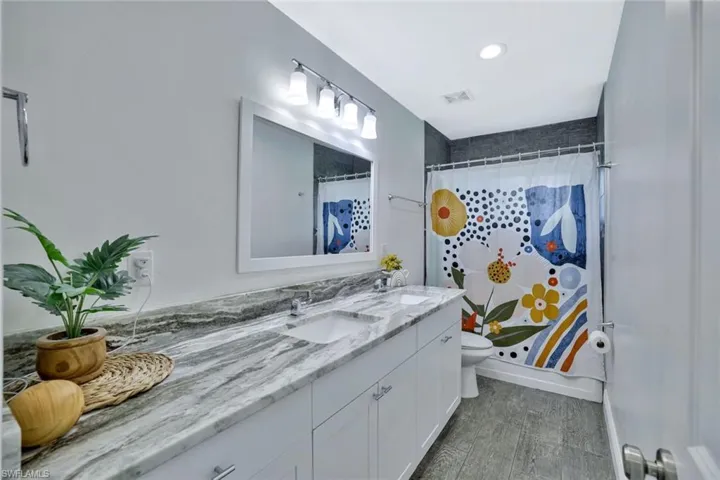 Bathroom featuring dual sinks, hardwood / wood-style floors, toilet, and large vanity