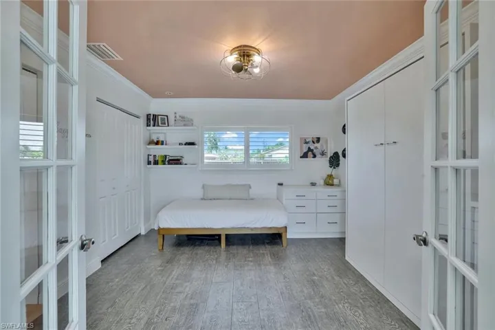 Bedroom with ornamental molding, hardwood / wood-style flooring, and french doors