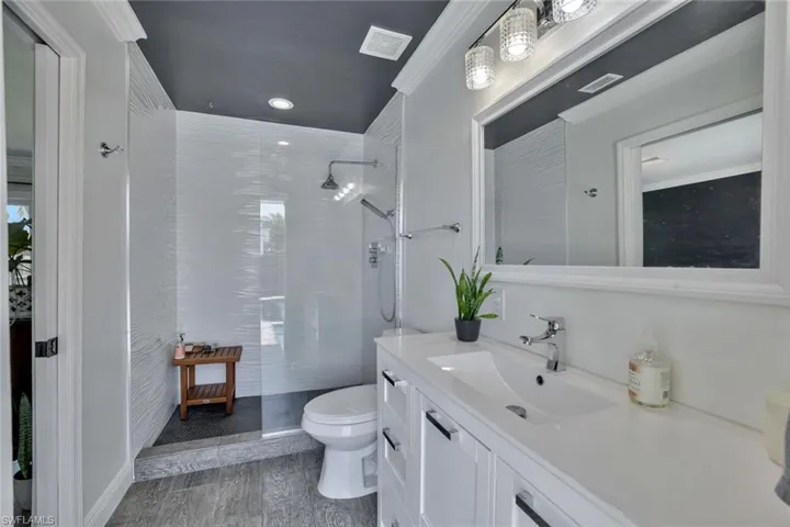 Bathroom featuring crown molding, hardwood / wood-style floors, walk in shower, toilet, and vanity