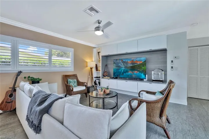 Living room with crown molding, hardwood / wood-style flooring, and ceiling fan