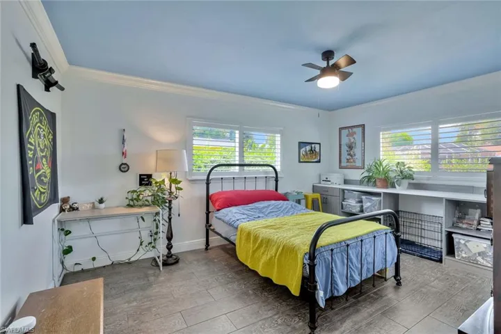 Bedroom with ceiling fan, hardwood / wood-style flooring, and ornamental molding