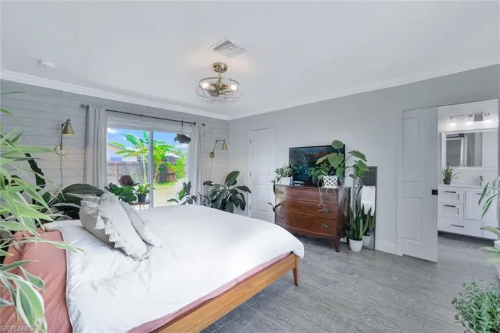 Bedroom with a notable chandelier, wood-type flooring, access to outside, and crown molding