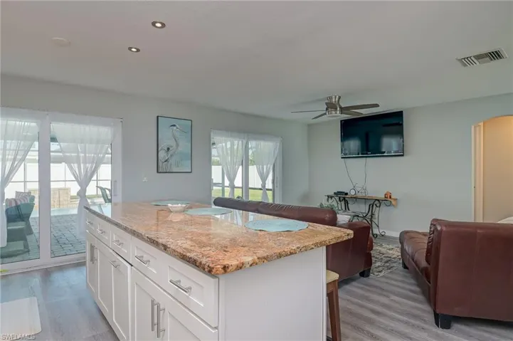 Kitchen featuring open floor plan, light stone countertops, arched walkways, a kitchen island, and a kitchen breakfast bar
