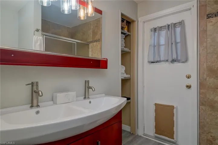 Full bath featuring double vanity, a shower with shower door, a closet, and a chandelier