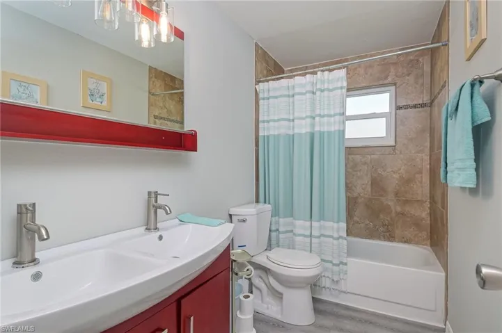Full bath with vanity, shower / bath combination with curtain, and light wood-style flooring